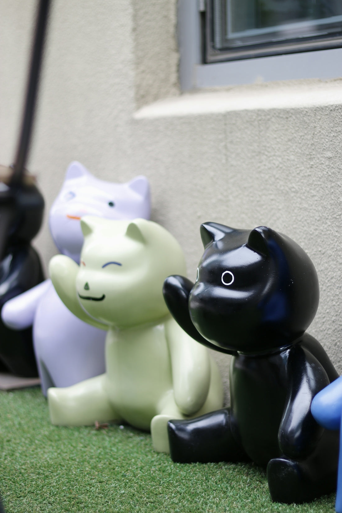 A row of black and white cats sitting next to a building