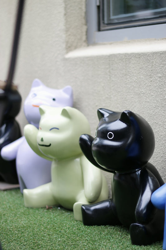A row of black and white cats sitting next to a building
